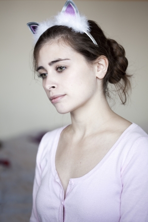 Head and shoulders portrait of a young adult Caucasian woman in her early 20's, wearing bunny ears and giving a contemplative gaze to the side with the slightest hint of a melancholic smile.の写真素材