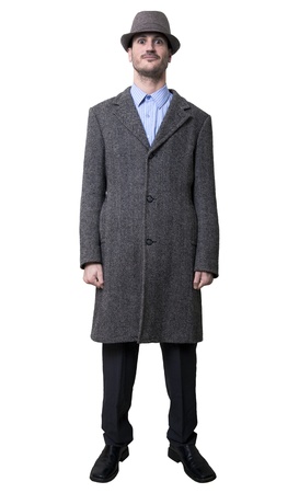 A young adult male wearing an overcoat and a matching hat, smiling and staring in an awkward manner to the camera.
Isolated on white background.の写真素材