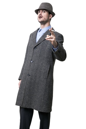 A person dressed in a gray overcoat and a gray hat shading his eyes. He seems to be angry, Pointing his hand holding a cigarette and wearing an intimidating facial experssion
Isolated on white background.の写真素材