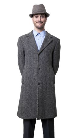 A young adult male wearing an overcoat and a matching hat, smiling and eyes wide open staring in an awkward manner to the camera.
Isolated on white background.の写真素材