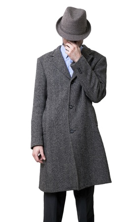 A young adult male wearing a gray overcoat and a gray hat that is hiding his eyes. He's massaging his nose and eyes with his left hand, as if to wake himself up.
Isolated on white background.の写真素材