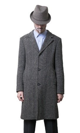 A person dressed in a gray overcoat and a gray hat that is completely hiding his eyes. Smoking a cigarette.
Isolated on white background.の写真素材