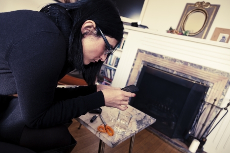 An adult caucasian woman in her early 30's using her smartphone while sitting at a living room. Vintage coloring applied.の写真素材