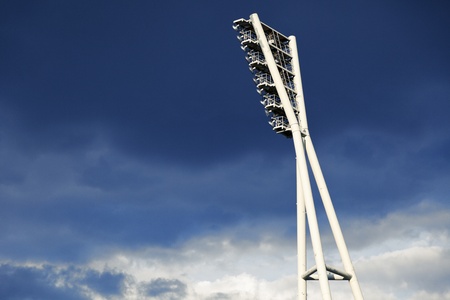 A tall lighting tower belonging to a sports stadium, on the background of dramatic sky with heavy clouds の写真素材