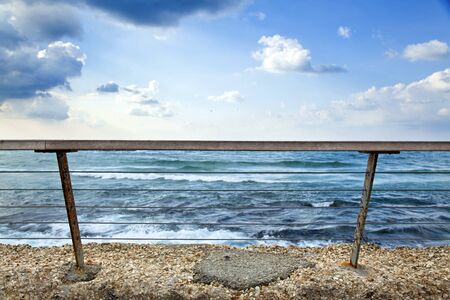 A banister attached to a wall, keeping people safe from falling to the gushing sea の写真素材