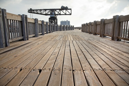Wooden deck boardwalk over the old wavebreaker in the old Tel-Aviv, which nowadays is a public commercial area. In the distance - a vintage derrick crane left at the pier as a historical reminder.の写真素材