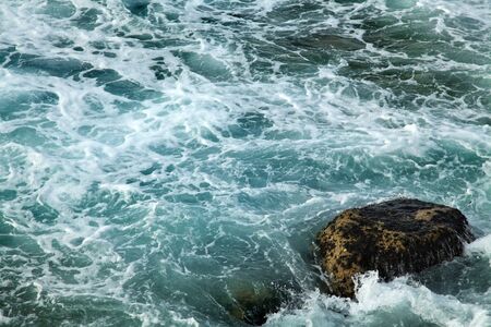Gushing water with foaming waves smashing against the rocks.