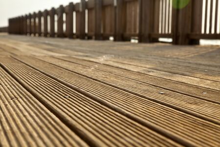 A wooden deck footpath in the sunlight, diminishing pespective.