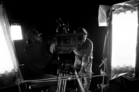 Tel-Aviv, Israel - February 3rd, 2012: Cinematographer and first assistant camera (focus puller) sitting on a camera dolly at work on a soundstage, surrounded by the lighting setup. のeditorial素材