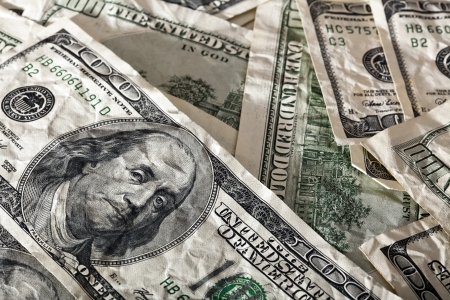 A close up high angle view of a very large amount of crumpled 100 US$ money notes in a bulky mess,...