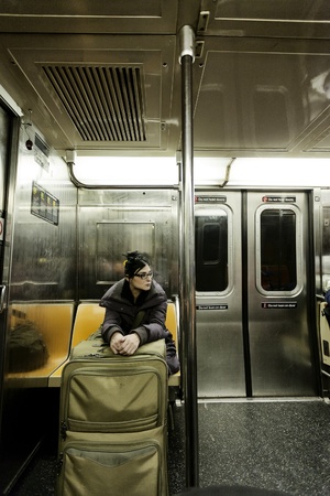 An adult woman with luggage sitting in the Brookly bound (downtown) A train subway in Manhattan.の写真素材