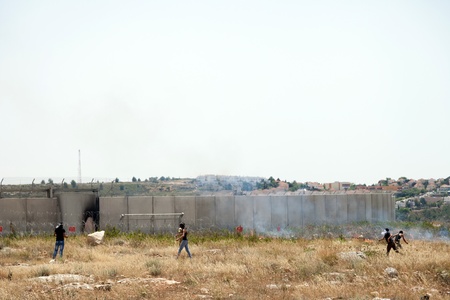 Bil'in, Palestine - May 17th, 2013: Two Palestinian youths throwing rocks towards the Israeli army force standing behind the wall of separation that is between them. This is part of the weekly demonstration taking place in the village of Bil'in.のeditorial素材