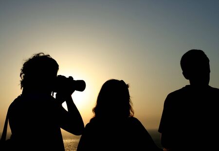 People in silhouette photographing the sunsetの写真素材