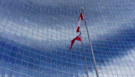 Canadian flag blowing in the wind against windowsの写真素材