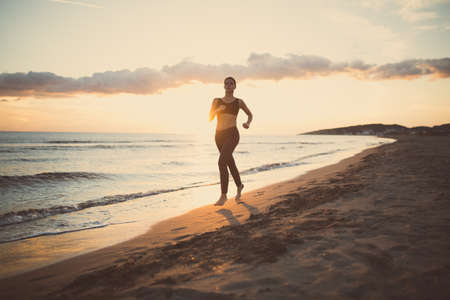 Runner woman jogging on beach in sports bra top.Beautiful fit female fitness woman training and...