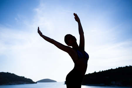 Carefree woman dancing in the sunset on the beach.Vacation vitality healthy living concept.Free woman enjoying freedom feeling happy at beach at sunset.Serene woman in pure happiness and enjoymentの写真素材