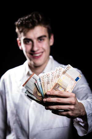 Male medicine cheerful doctor holding in hands euro banknotes.Medic salary, prestige and high paid job, education, public health business, medical insurance concept.Bribe and corruption conceptの写真素材