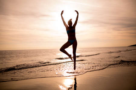 Carefree woman dancing in the sunset on the beach.Vacation vitality healthy living concept.Woman practicing yoga and meditating.Serene woman in pure happiness and enjoymentの写真素材
