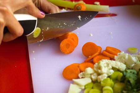 A young woman chops carrots with a big knife.の写真素材