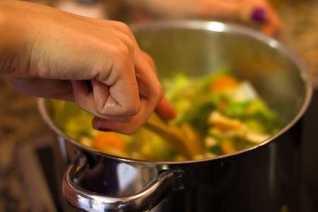 A young woman cooks vegetables in a casserole.の写真素材