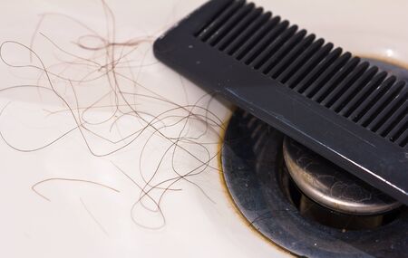 Dirty bathroom sink full of hair and a comb, concept for hair loss.の写真素材