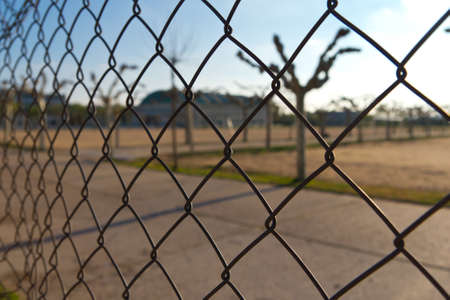 Detail of a wire netting with selective focus and a park behind it.の写真素材