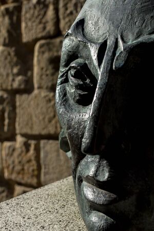 Close up of an iron head bust, with half of the face in the shadows.の写真素材