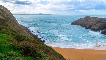 A paradise empty beach in Cantabria, with mountains and cliffs surrounding the beach.の写真素材
