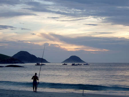 Fishing on the sunset at the beach in Niterói, Rio de Janeiro, Brazilの写真素材