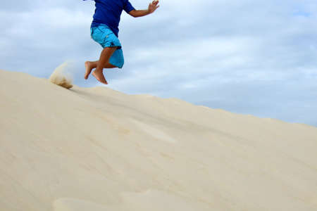 Child playing in the sand dune in South of Brazilの写真素材