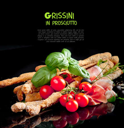 Grissini with prosciutto crudo and vegetables on blackの写真素材