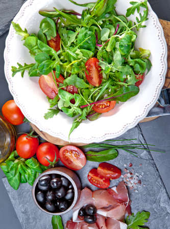 Sliced prosciutto with salad and oliveの写真素材