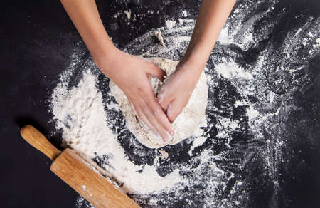 Baking preparing background. Female hands knead dough on the worktop.