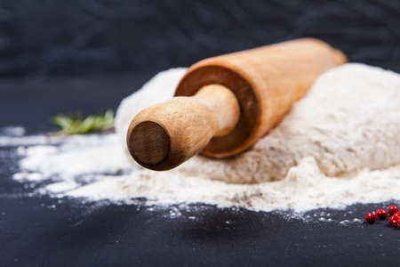 Fresh pizza dough with natural ingredients for cooking on black tableの写真素材