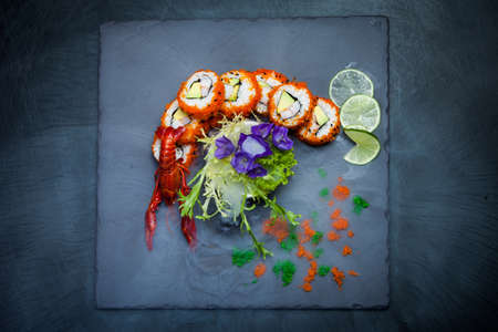 Sea crawfish and sushi on a slate dark plate with liquid smokeの写真素材
