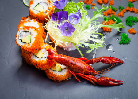 Sea crawfish and sushi on a slate dark plate with liquid smokeの写真素材