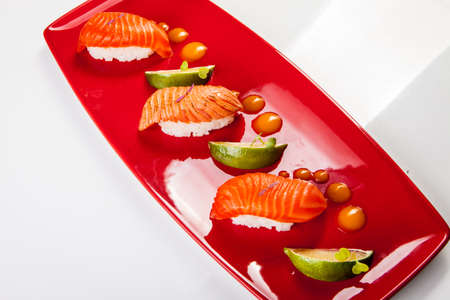 Sushi on red plate served with lime. Isolated on white. Sushi on red plate served with lime. Isolated on white.