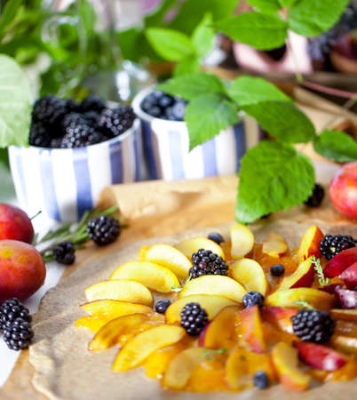 Preparation of whole-grain galette with plums on a white table. top view