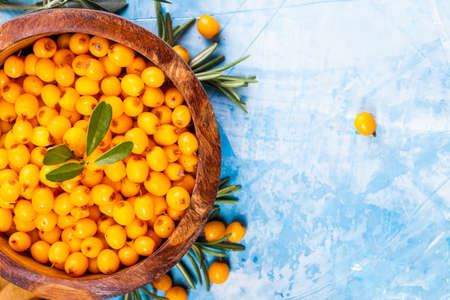 Sea buckthorn berries on wooden bowl on bright background.の写真素材
