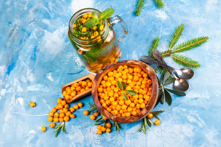 Sea buckthorn berries on wooden bowl on bright background.の写真素材
