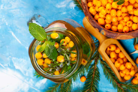 Sea buckthorn berries on wooden bowl on bright background.
