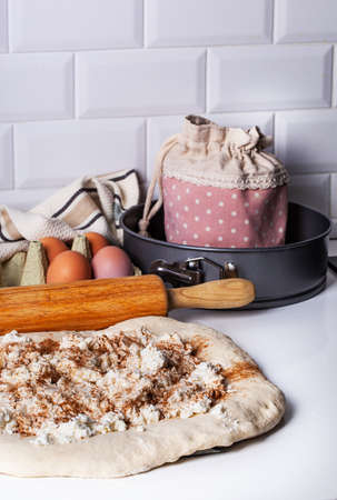 Raw yeast dough covered with a towel in a bowl on the floured kitchen table, recipe idea. Concept...