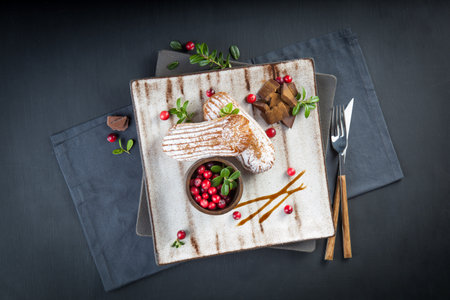 Cream eclairs choux pastries served with fresh cranberries on a handmade ceramic plate