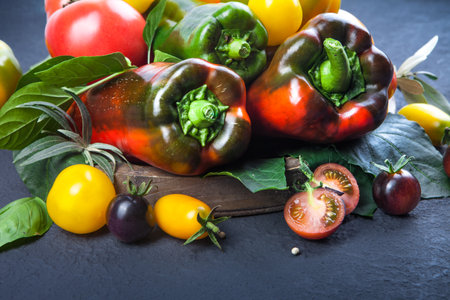 Assorted tomatoes and vegetables isolated on dark background.の写真素材