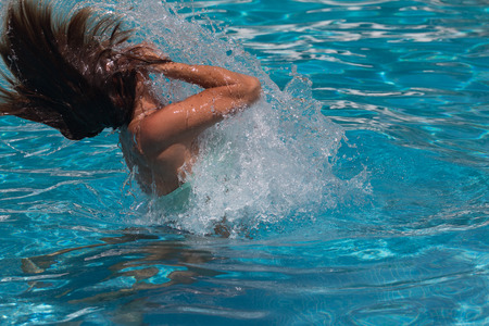 Woman shaking her hair as she leaves the pool to splash waterの写真素材