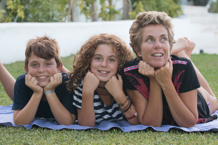 Happy family made of a mother and her two children, a boy and a girl photographed in a garden during the summerの写真素材
