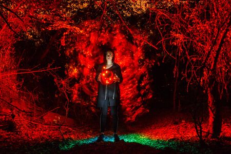 witch playing with lights like fire in the forest during halloweenの写真素材