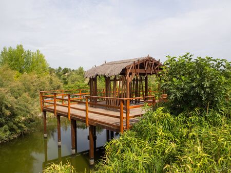 wooden shed in the middle of a large vegetation and on a small lagoonの写真素材