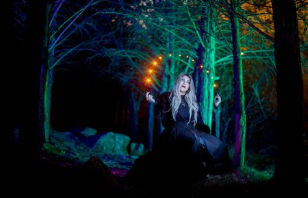 Portrait of a girl in the dark forest with colorful lights around herの写真素材