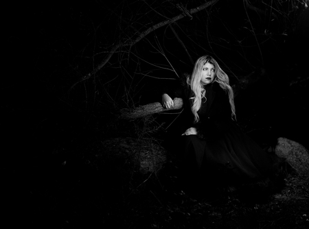 Portrait of a woman leaning on a tree in the darkの写真素材